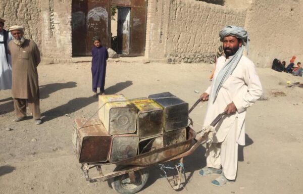 A man is on his way to collect water for his family from an open stream.