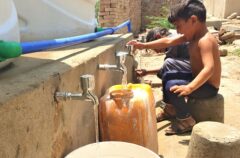 A couple of children laughing and playing while collecting clean water from the collection point rehabilitated by Cesvi in the village.